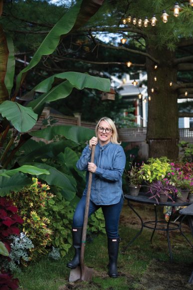 Melissa is shown in her backyard with banana plants, coleus, purpleheart and Gomphrena in the background. Her backyard lights are by Smith & Hawken from Target.