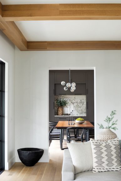 DINING IN STYLE

A black walnut table, cut from a tree in the backyard and custom-built by Aldo Partners, lends warmth to the dark-hued dining room. “Everything else needed to be in service to this special piece,” Simpson says. The accompanying design details include a modern light fixture that’s “impactful without distracting from the lake view,” she notes.