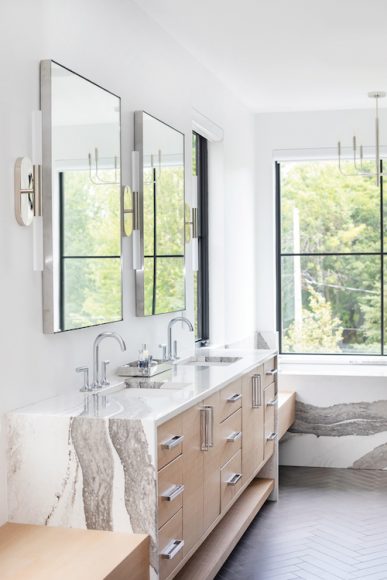 The primary bath features a large steam shower, which Tom says is particularly welcome in the winter. The quartz waterfall countertop and herringbone flooring continue the luxe feel.