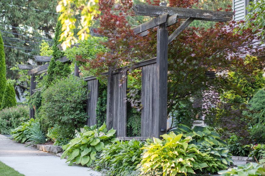 A Japanese maple and hostas surround a wooden structure, built by local craftsman Steve Rose, out of reclaimed Douglas fir. It allows for both privacy and interaction with neighbors.