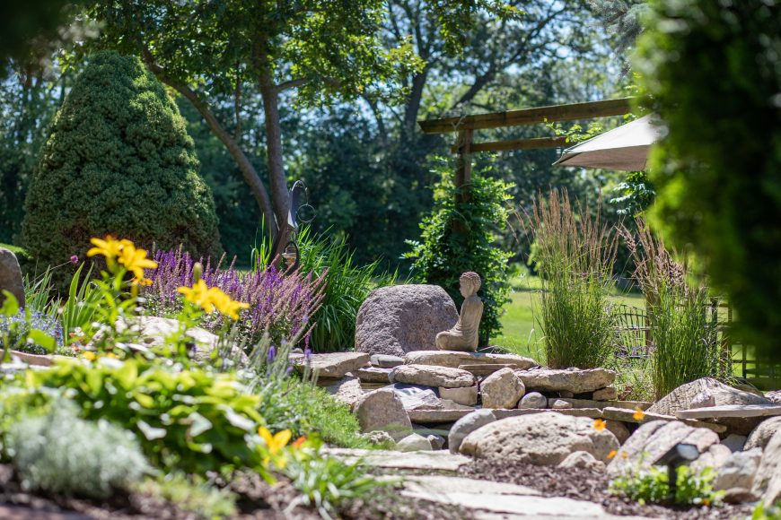 Purple irises, yellow lilies, blooming moss and lavender punctuate the garden while a Buddha statue watches calmly over a pond, secluded by grasses. At night, the garden’s pathway is lit.
