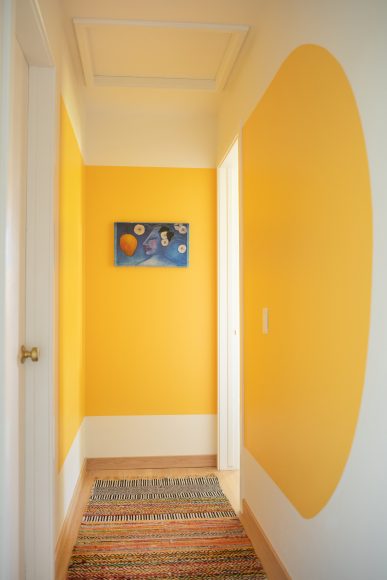 For a touch of whimsy, Drammeh painted a yellow scallop in the upstairs hallway. The baseboards are oak, unlike the adjacent white casings. “That way you don’t see the dust on the baseboards!” Drammeh says, a trick she learned while running a housecleaning business.