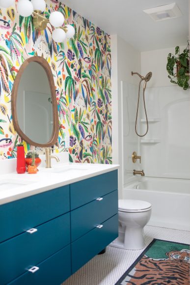 To pull attention away from the plain fiberglass shower and tub in her son’s bathroom, Drammeh created a feature wall with colorful wallpaper and asymmetrical mirrors. The finger-pull hardware on the vanity lends a playful touch, fitting for a child’s bathroom.