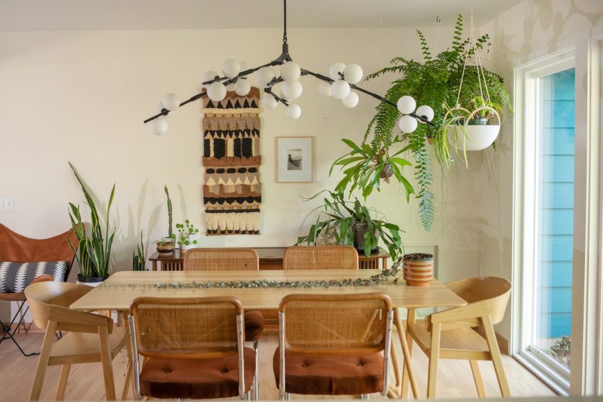 A striking black chandelier arcs over the dining table, which Drammeh selected for its sense of motion and because its form mimics the surrounding plants. She found the 1970s-era dining chairs on Facebook Marketplace and the vintage fiber arts wall hanging at Madison’s Atomic Antiques.