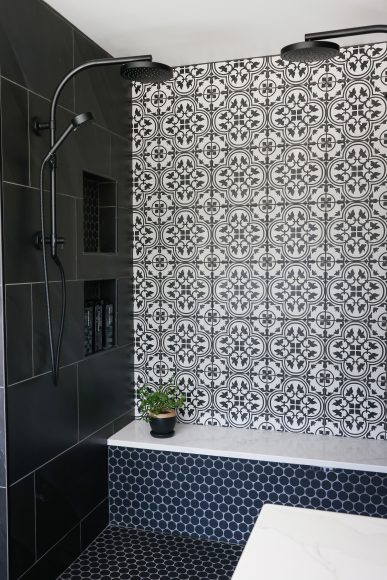The new walk-in shower features double shower heads and plenty of product niches, while the patterned ceramic tile pairs well with the glass penny tile on the shower bench and the floor. 