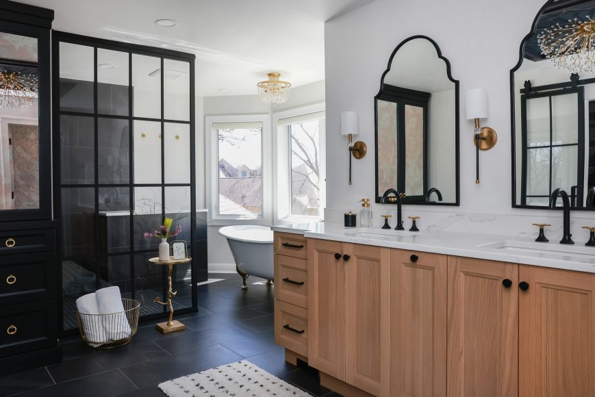 AFTER: Swapping out a whirlpool tub with decking for a freestanding, clawfoot soaking tub by Signature Hardware opened up and modernized the bathroom and allowed for the creation of a larger, curbless shower. An attractive glass partition wall denotes the bathoom’s “wet” area.