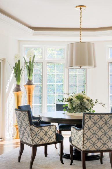 The home’s breakfast nook features a custom-made round table accented by a scalloped linen hanging shade from Visual Comfort.