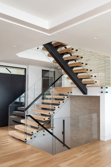 An arresting glass floating staircase connects the home’s four floors and is accented by an attractive stone wall. Cox gathered design ideas for both the closet and staircase from home renovation shows.