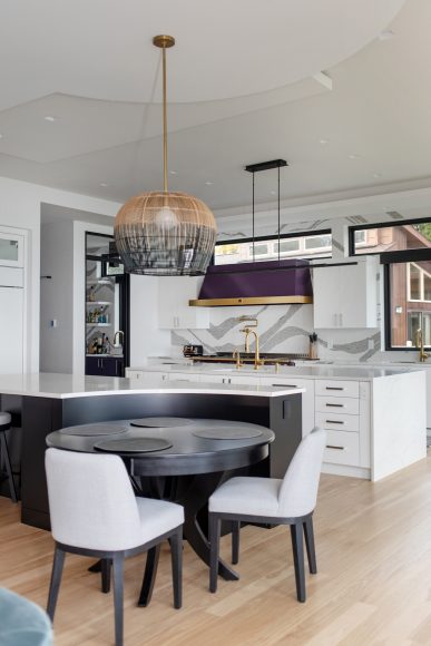 The kitchen features two islands, one of which contains a curved banquette. The striking, contemporary light fixture over the dining table took the electrician one week to hang. Like most of the home’s light fixtures, it came from Madison Lighting.