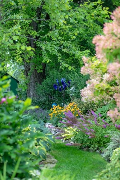 The tall, blue flower-like structure is a blue bottle tree, with native black- eyed Susans, astilbes and Miss Kim lilacs surrounding it.