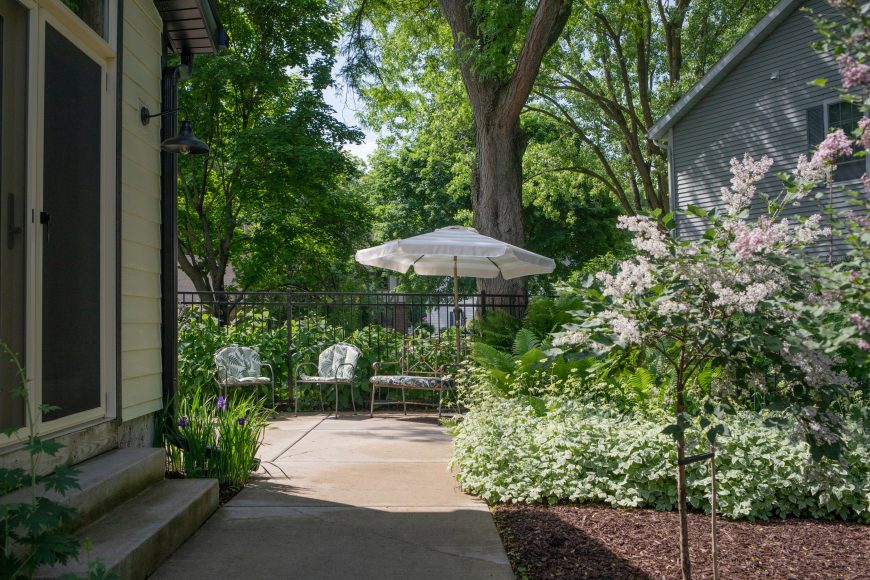 Vaughan’s backyard has a few distinct zones, including this peaceful lounging area. A honey locust tree is located behind her patio umbrella that provides copious shade. Adjacent to her back door are three lilac trees planted in a row. “They’re kind of like topiaries — they won’t get big. They look cute when they’re in bloom,” she says.