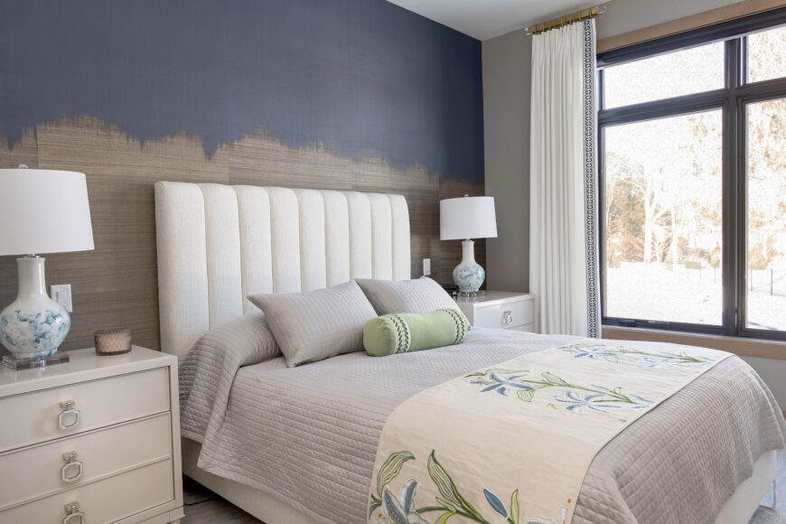 The primary bedroom’s tall, upholstered headboard is great for reading in bed. Metallic ombre wallpaper by Phillip Jeffries makes a statement in the primary bedroom.