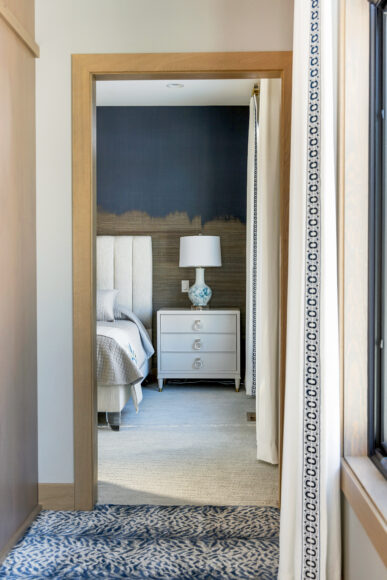 The guest suite’s night table is finished with lacquered grasscloth. Gold is woven in as an accent throughout the home, including in the lamps and furniture hardware in the guest room.