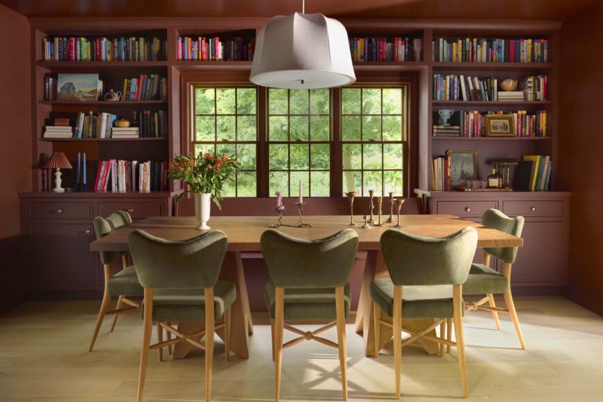 The couple’s dining room, painted in Benjamin Moore’s Ruby Dusk, incorporates built-in bookshelves, giving it a comfy, library feel. To soften the space, designer Katie Calnin selected a rattan and linen dome pendant from Crate & Barrel, and Pierce & Ward curved-back chairs covered in juniper velvet (available through West Elm).