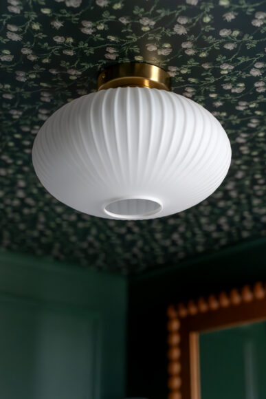 Hansen sourced Astek Home’s “Irene” wallpaper for the ceiling, which she notes is an authentic 1920-30s-era pattern. KCO’s White Ribbed Glass Semi Flush Mount Ceiling Light dresses up the space and was purchased on Amazon.