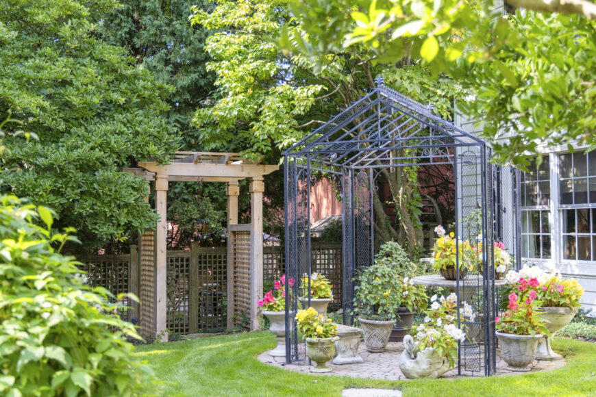 The decorative metal garden pavilion creates a dramatic focal point in Marilyn Blettner’s backyard, combining the elegance of a gazebo with the openness of an arbor. Its geometric framework is also an ideal structure for climbing vines and flowering plants. Positioned amid colorful container gardens and lush greenery, it helps define the outdoor space and creates an inviting garden retreat.