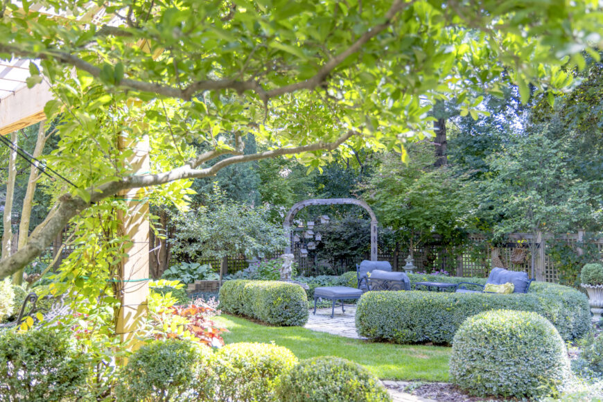 The curved wooden garden archway creates a welcoming transition between outdoor spaces.