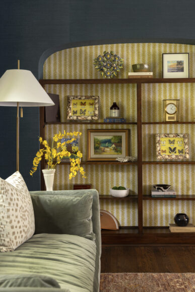 In one of their riskier design decisions, Payne says, “we chose this funky yellow wallpaper to [infuse] personality and brightness into what is a moody space.” She and Sam Pelot of Sam Pelot Interiors + Collections curated the decor for the living room bookshelf, including a Tiffany clock and art from the family’s travels.