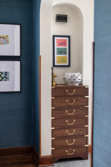 This custom mail cabinet was inspired by vintage Henredon campaign furniture and features trompe l'oeil drawers. The art that hangs in the home is “all one-of-a- kind or things they’ve collected, which is really personal,” says Payne.